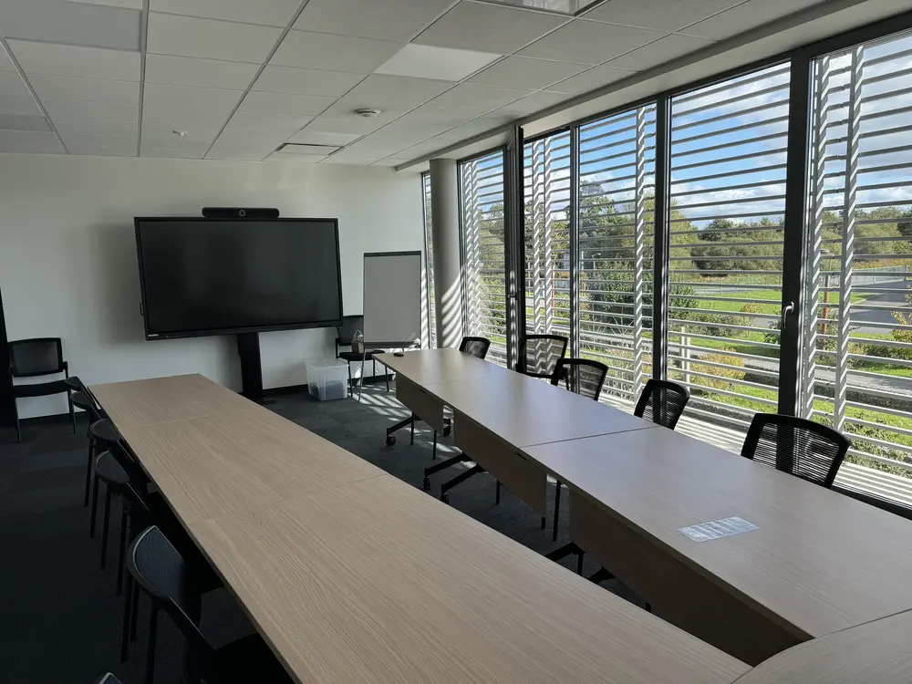 photo de la salle de formation du centre de formation West Academy avec vue sur la table centrale devant l'ecran de visioconférence et vue sur l'extérieure