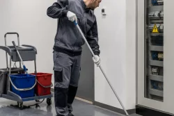 vu d'un agent de nettoyage entrain de travailler à coté d'une armoire électrique